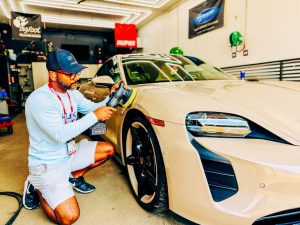 Joseph Stein polishing a Porsche Taycan and applying ceramic coating at Lava GR Auto Detailing in Wyoming, Michigan