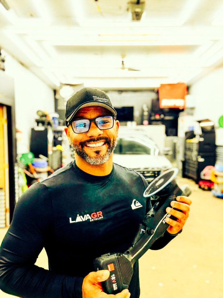 Joseph Stein holding a Rupes polishing machine at Lava GR Auto Detailing shop in Grand Rapids Michigan