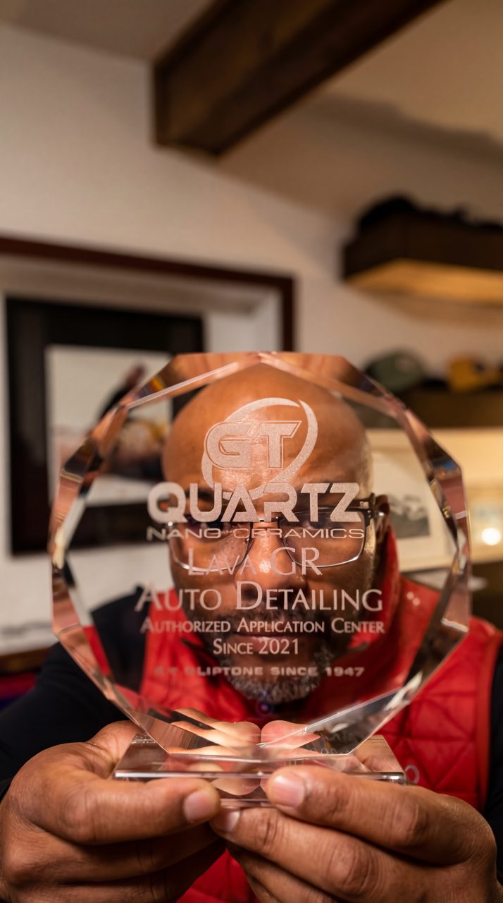 Joseph Stein holding GT Quartz ceramic coating certification plaque inside Lava GR Auto Detailing shop in Wyoming Michigan.