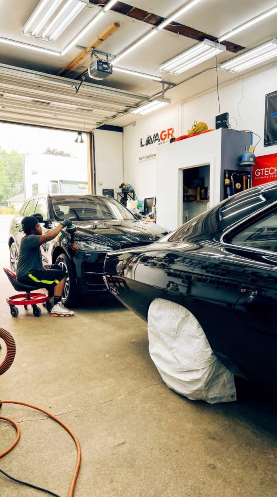 Auto detail technician polishing vehicle paint inside Lava GR Auto Detailing shop.